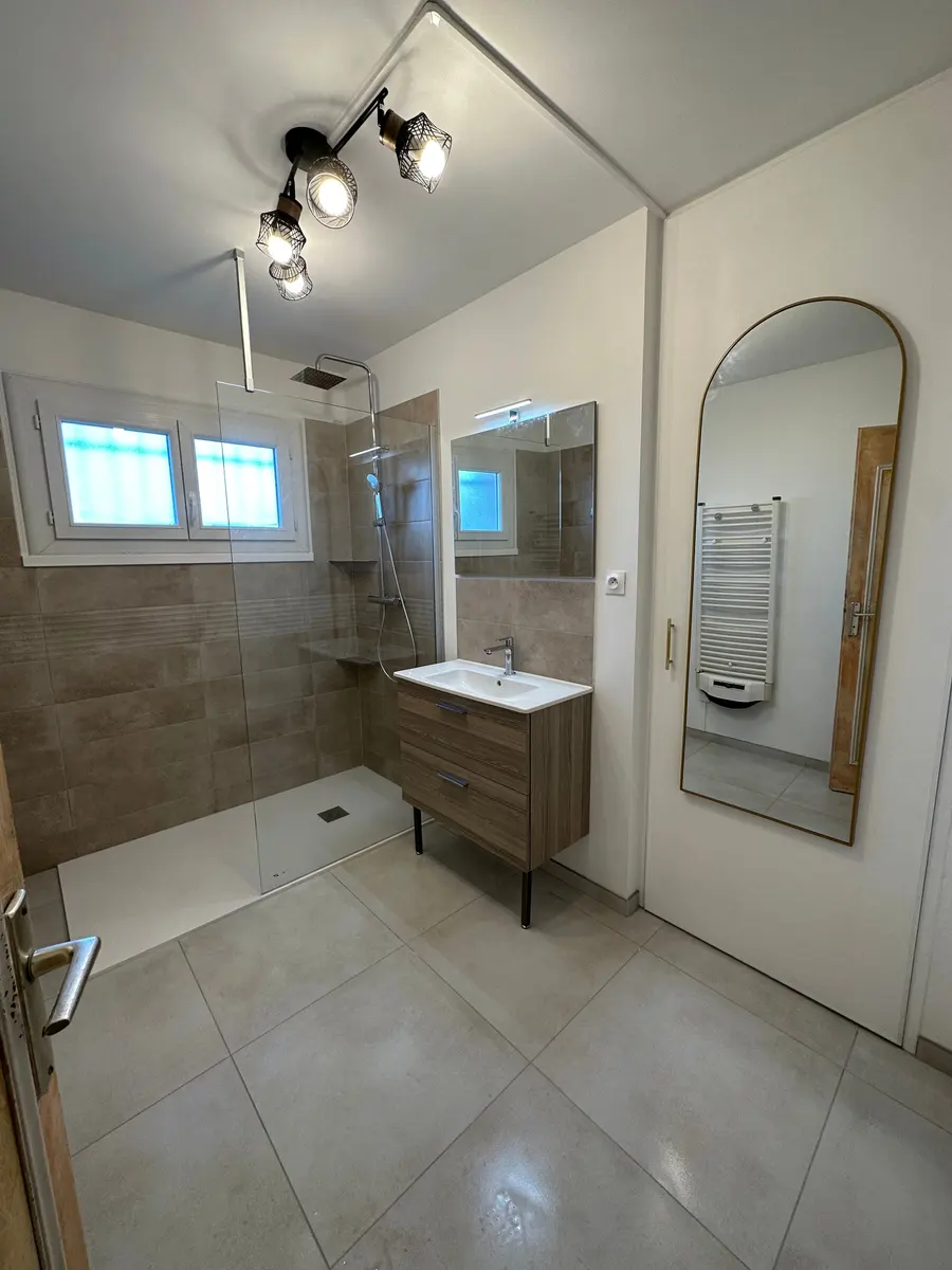 Salle de bain travertin avec baignoire et robinetterie noire